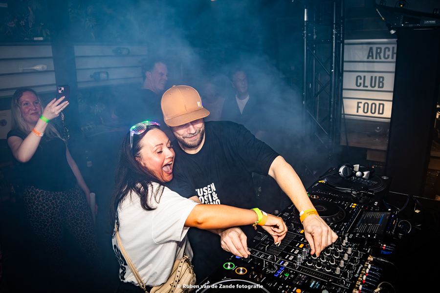 Bezoeker en dj samen achter de draaitafels