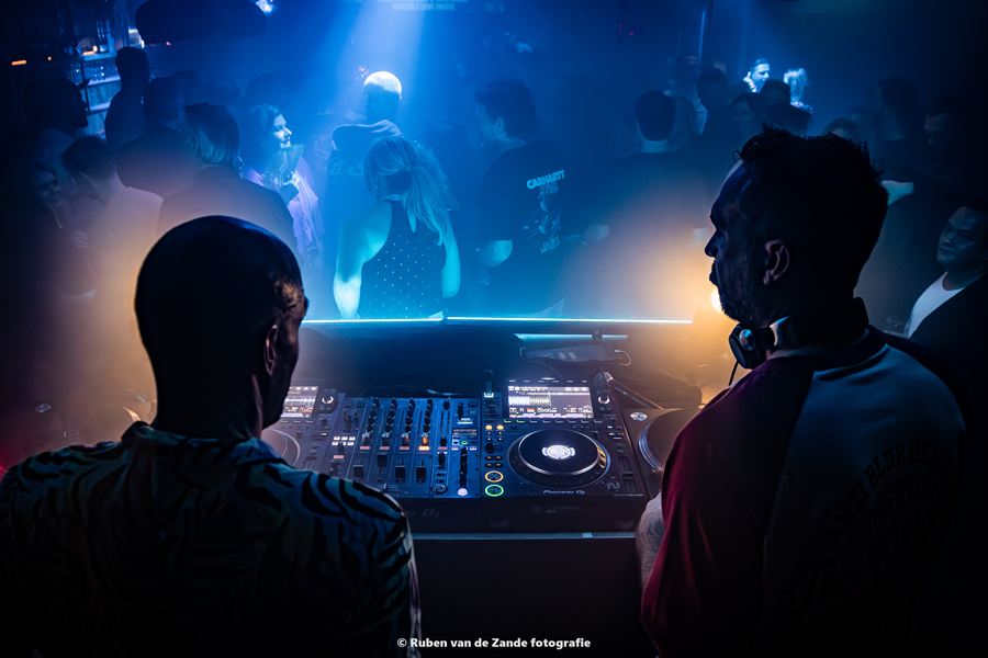 Silhouetten van bezoekers voor de verlichte dj-booth